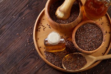 Ahşap arka plan, üstten görünüm, yakın çekim, seçici odak cam şişede kase ve keten tohumu yağı keten tohumu