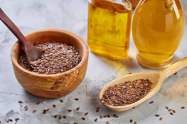 Semillas de lino en cuenco y aceite de linaza en botella de vidrio sobre fondo de madera, vista superior, primer plano, enfoque selectivo — Foto de Stock