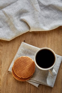 Pamuk peçeteye bir rustik ahşap arka plan, üstten görünüm, dikey olarak waffle ile porselen çay fincanı