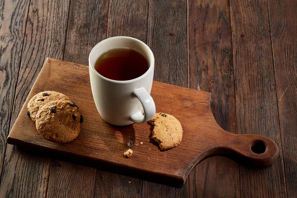 Xícara de chá com biscoitos, caderno de exercícios e um lápis em um fundo de madeira, vista superior — Fotografia de Stock