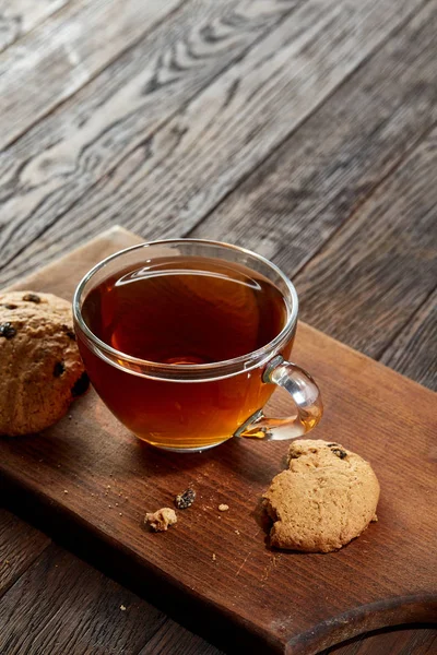 Taza de té con galletas en una tabla de cortar sobre un fondo de madera, vista superior — Foto de Stock