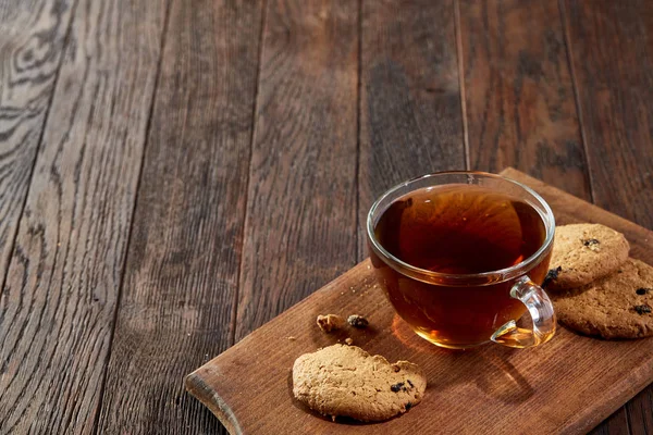 Taza de té con galletas en una tabla de cortar sobre un fondo de madera, vista superior — Foto de Stock