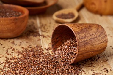 Linseeds bir rustik arka plan, yakın çekim, sığ alan, seçici odak derinliği ile devrilmiş bir ahşap kase