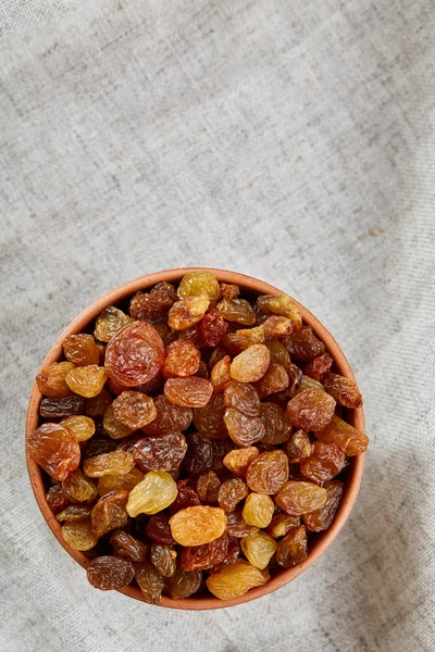 Wooden bowl with golden raisins on light tablecloth, close-up, selective focus — Stock Photo, Image