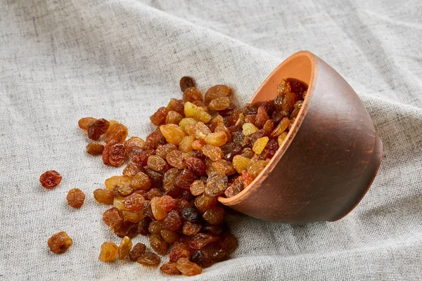 Tigela de madeira com passas douradas na toalha de mesa leve, close-up, foco seletivo — Fotografia de Stock