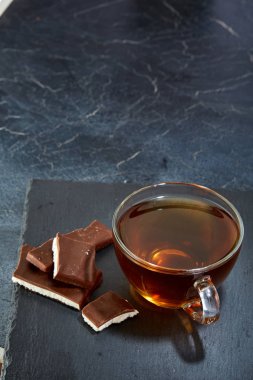 Bir cam fincan çikolata koyu grimsi mermer zemin, sığ derinlik-in tarla ile siyah çay. Kahvaltı arka plan