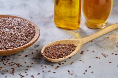 Işık cam şişede kase ve keten tohumu yağı keten tohumu dokulu arka plan, üstten görünüm, yakın çekim, seçici odak