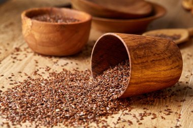 Linseeds bir rustik arka plan, yakın çekim, sığ alan, seçici odak derinliği ile devrilmiş bir ahşap kase