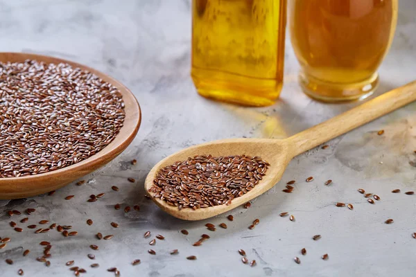 Işık cam şişede kase ve keten tohumu yağı keten tohumu dokulu arka plan, üstten görünüm, yakın çekim, seçici odak