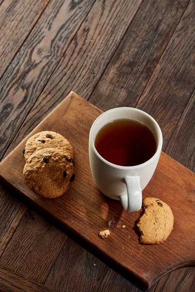 Cup of tea with cookies on a wooden cutting board on vintage background, top view — Stock Photo, Image