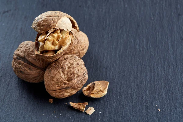 Top view close-up shot of cracked walnuts on dark background, shallow depth of field, macro