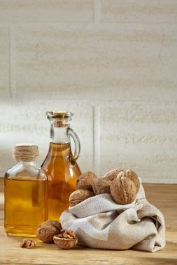 Aromatik yağ bir cam kavanoz ve şişe ahşap masa, yakın çekim, dikey torba ceviz ile