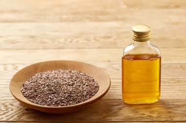 Ahşap arka plan, üstten görünüm, yakın çekim, seçici odak cam şişede kase ve keten tohumu yağı keten tohumu