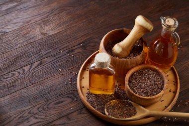 Ahşap arka plan, üstten görünüm, yakın çekim, seçici odak cam şişede kase ve keten tohumu yağı keten tohumu