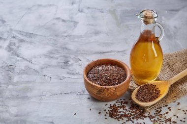 Işık cam şişede kase ve keten tohumu yağı keten tohumu dokulu arka plan, üstten görünüm, yakın çekim, seçici odak