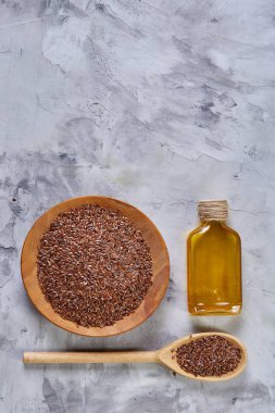 Işık cam şişede kase ve keten tohumu yağı keten tohumu dokulu arka plan, üstten görünüm, yakın çekim, seçici odak