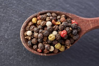 En koyu arka plan üzerinde tahta kaşık karabiber bileşimi görünüm yakın çekim.