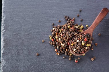 En koyu arka plan üzerinde tahta kaşık karabiber bileşimi görünüm yakın çekim.