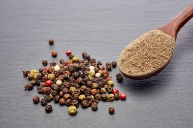 En koyu arka plan üzerinde tahta kaşık karabiber bileşimi görünüm yakın çekim.