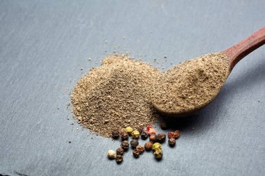 En koyu arka plan üzerinde tahta kaşık karabiber bileşimi görünüm yakın çekim.