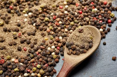 En koyu arka plan üzerinde tahta kaşık karabiber bileşimi görünüm yakın çekim.