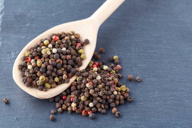 En koyu arka plan üzerinde tahta kaşık karabiber bileşimi görünüm yakın çekim.