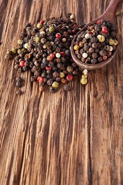 Draufsicht auf schwarze, rote und weiße Pfefferkörner isoliert auf Holzgrund, geringe Schärfentiefe. — Stockfoto