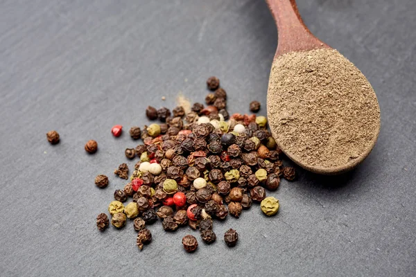 En koyu arka plan üzerinde tahta kaşık karabiber bileşimi görünüm yakın çekim.