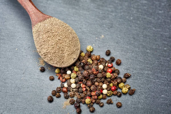 En koyu arka plan üzerinde tahta kaşık karabiber bileşimi görünüm yakın çekim.