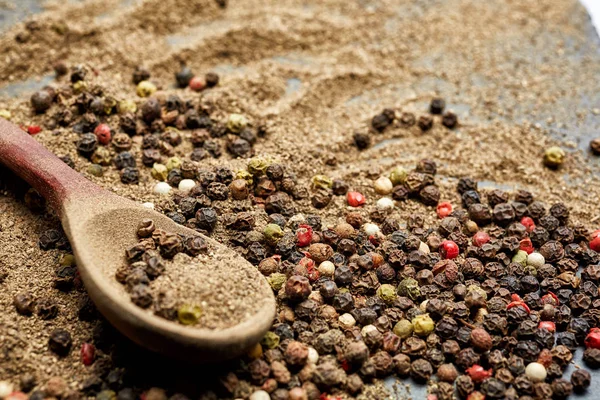 Top view on composition of peppercorns in wooden spoon on dark background, close-up. — Stock Photo, Image