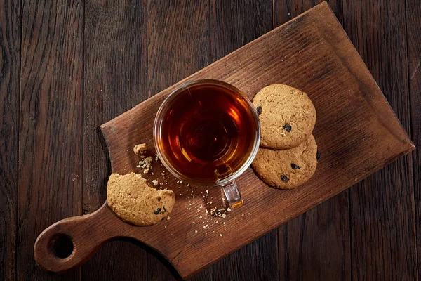 Cup of tea with cookies on a cutting board on a wooden background, top view — Stock Photo, Image
