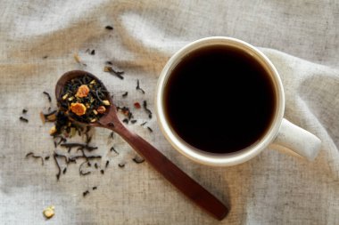 Rustik ahşap arka plan, seçici odak bir peçeteye dağınık çay yapraklar ile fincan seramik