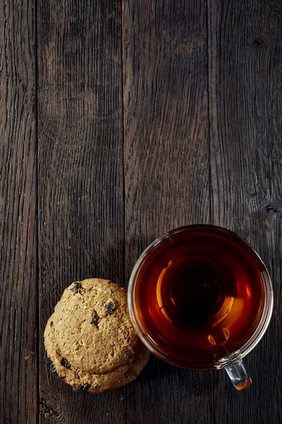 Скляна чашка з печивом з шоколадних чіпсів на бавовняній серветці на сільському дерев'яному фоні, вид зверху — стокове фото