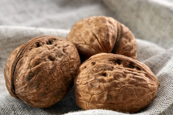 A stack of hard shells of walnuts piled together on light grey fabric cotton tablecloth, selective focus