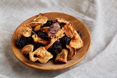 Yakın çekim ahşap kase kuru meyveler üzerinde hafif bir masa örtüsü ile