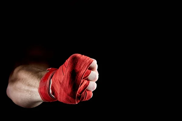 Uma bandagem vermelha boxers em sua mão isolado em fundo escuro desfocado, close-up . — Fotografia de Stock