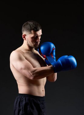 Düşük anahtar stüdyo portre yakışıklı kaslı Fighter boks koyu arka plan bulanık üzerinde pratik