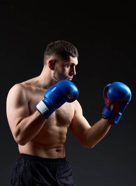 Düşük anahtar stüdyo portre yakışıklı kaslı Fighter boks koyu arka plan bulanık üzerinde pratik