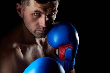 Agresif bir kaslı savaşçı, yumruğunu izole koyu arka plan üzerinde gösterilen düşük anahtar portresi kapatın.