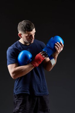 Düşük anahtar stüdyo portre yakışıklı kaslı dövüşçülerin korku koyu arka plan bulanık boks için hazırlanıyor