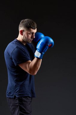 Düşük anahtar stüdyo portre yakışıklı kaslı dövüşçülerin korku koyu arka plan bulanık boks için hazırlanıyor