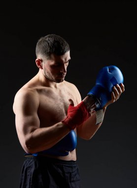 Düşük anahtar stüdyo portre yakışıklı kaslı dövüşçülerin korku koyu arka plan bulanık boks için hazırlanıyor