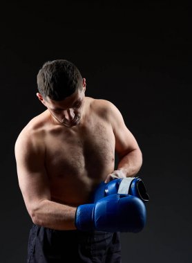 Düşük anahtar stüdyo portre yakışıklı kaslı dövüşçülerin korku koyu arka plan bulanık boks için hazırlanıyor