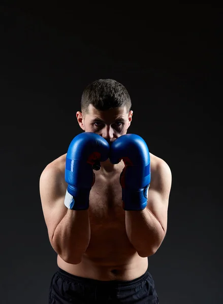 Nízké klíčových studiový portrét pohledný svalnatý bojovník cvičí boxu na tmavé rozmazané pozadí — Stock fotografie