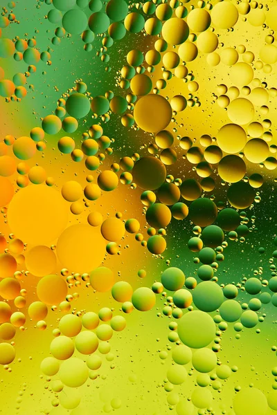 Water en olie mengen, mooie kleur abstract achtergrond op basis van groene en gele cirkels, ovalen, macro abstractie — Stockfoto