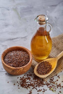 Işık cam şişede kase ve keten tohumu yağı keten tohumu dokulu arka plan, üstten görünüm, yakın çekim, seçici odak