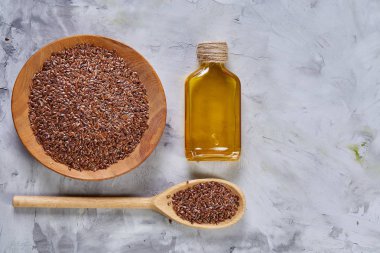 Işık cam şişede kase ve keten tohumu yağı keten tohumu dokulu arka plan, üstten görünüm, yakın çekim, seçici odak