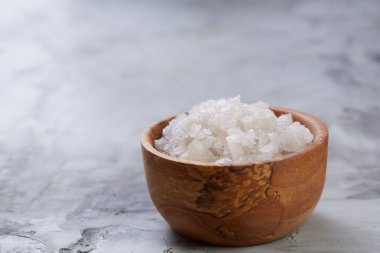 Büyük beyaz deniz tuzu bir doğal ahşap kase beyaz arka plan, üstten görünüm, yakın çekim, seçici odak