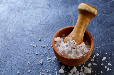 Doğal ahşap harç havaneli koyu arka plan, üstten görünüm, yakın çekim, seçici odak ile büyük beyaz deniz tuzu