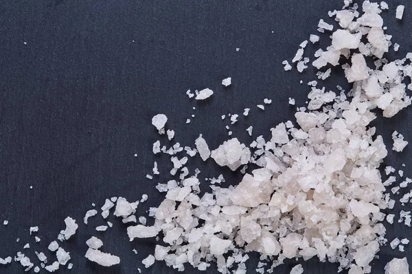 Pile of salt crystals isolated over the dark background, close-up, top view, macro, selective focus
